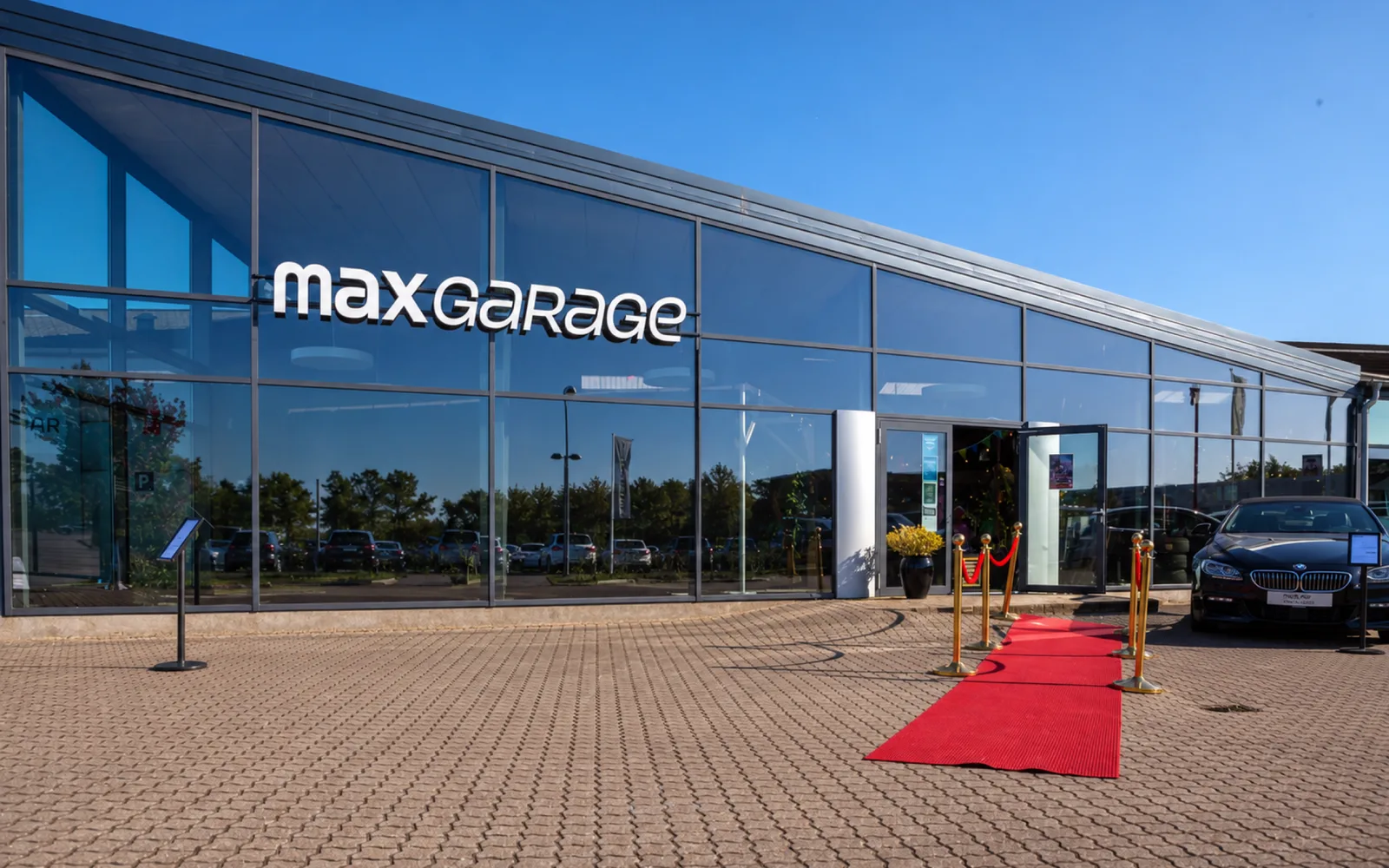 Max Garage Frederikssund med glasfacade, skilt og rød løber ved indgangen