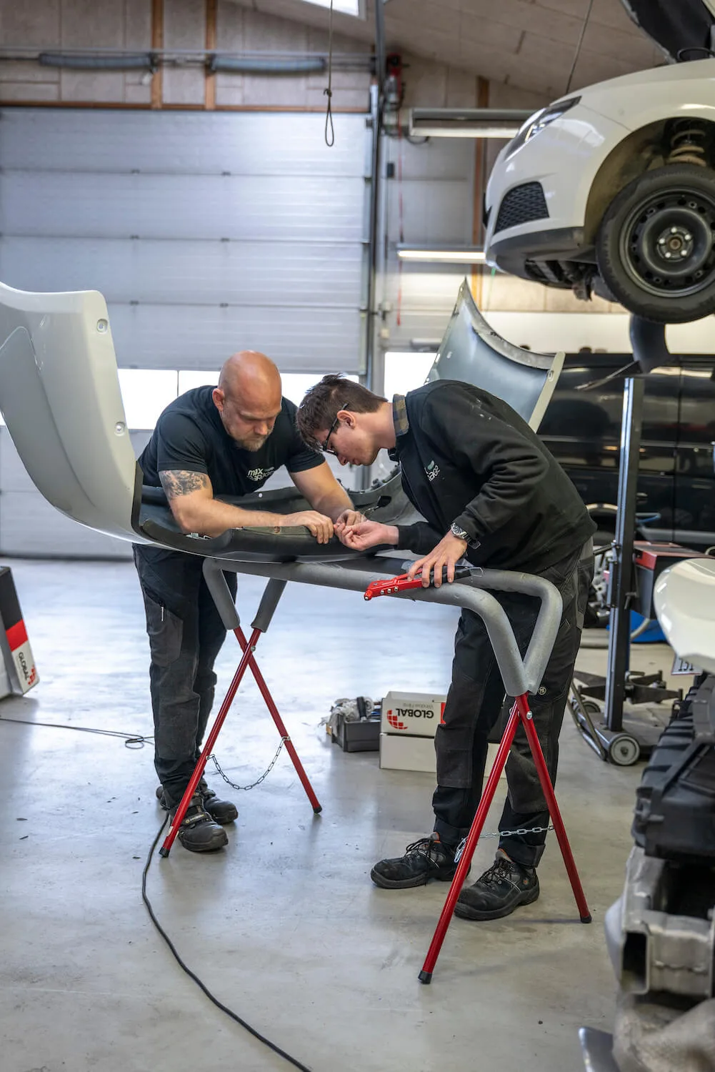 To mekanikere hos Max Garage arbejder sammen om en reparation